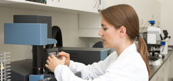 woman in lab coat adjusting a machine