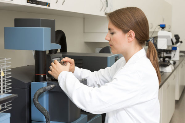 woman in lab coat adjusting a machine