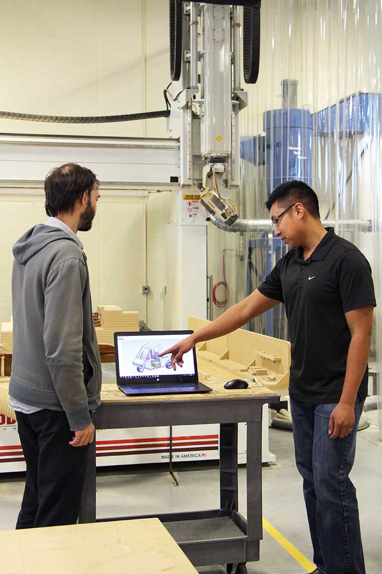 two people in a factory referring to information on a computer